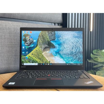 Matte black Lenovo ThinkPad T14 laptop open on a wooden desk showing the iconic red TrackPoint.